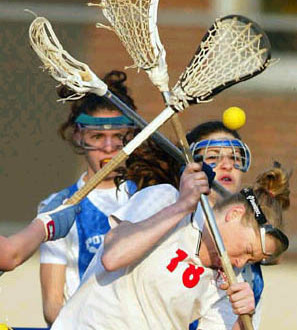 girl getting hit in the head with yellow lacrosse ball with 2 girls standing in the background standard equipment yellow lacrosse ball