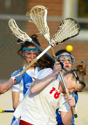 girl getting hit in the head with yellow lacrosse ball with 2 girls standing in the background standard equipment yellow lacrosse ball