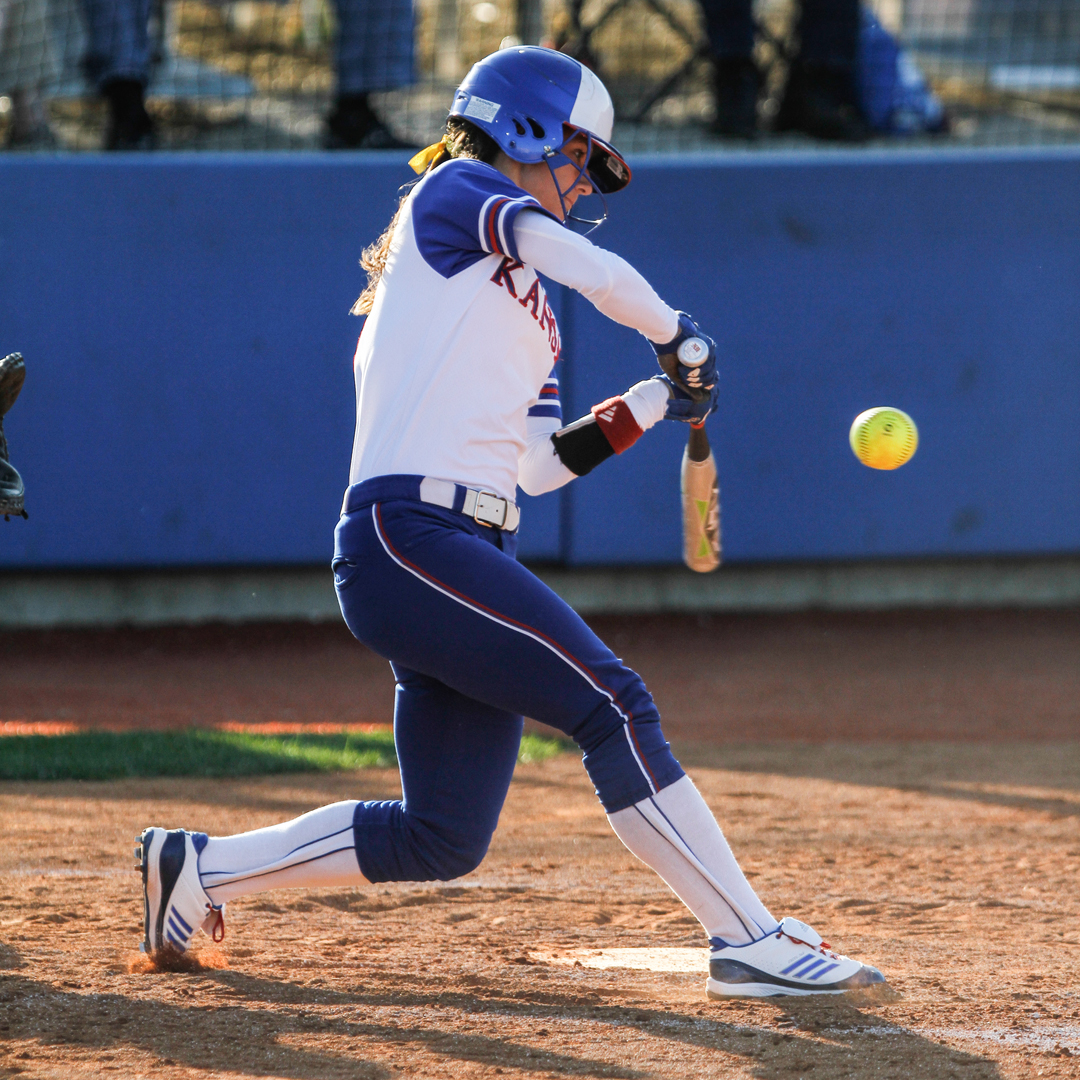 girl player about to hit a yellow softball standard equipment for softball yellow with red string softball softball bat and helmet