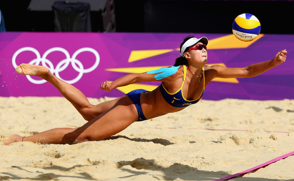 olympic beach volleyball player diving for yellow volley ball