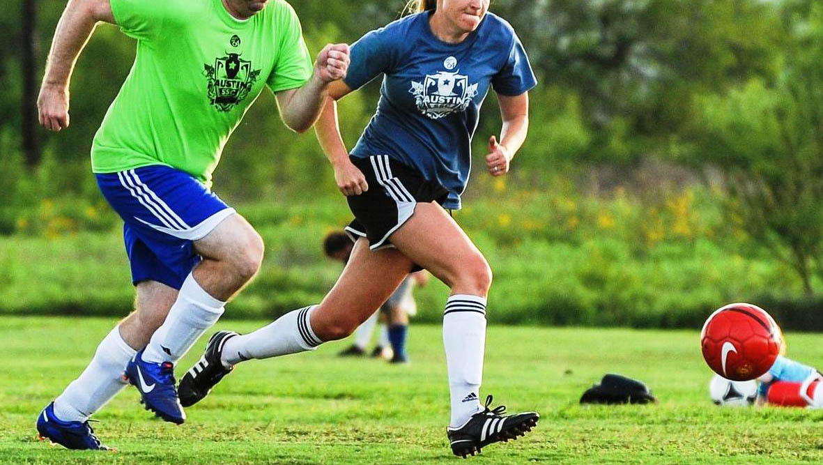 man and woman chase after soccer ball regulated equipment for soccer ball