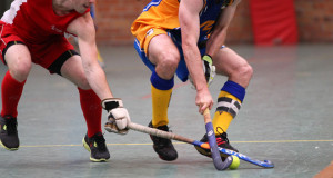 2 players going for the same ball indoor field hockey standard field hockey equipment field hockey stick and field hockey ball