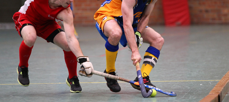 2 players going for the same ball indoor field hockey standard field hockey equipment field hockey stick and field hockey ball