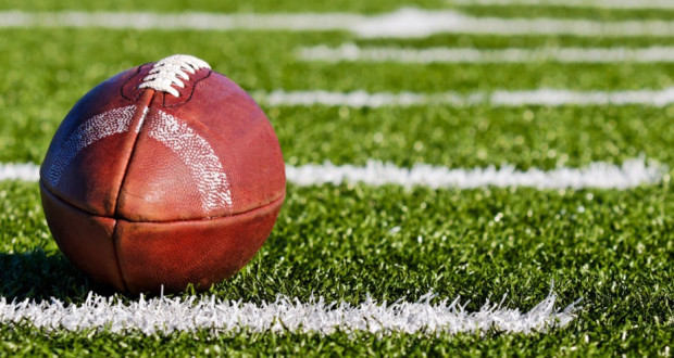 american football laying on a field with the laces pointing up official high school standard equipment football ball