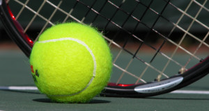 tennis ball on the ground of a tennis court with a tennis racquet behind it basic equipment for tennis
