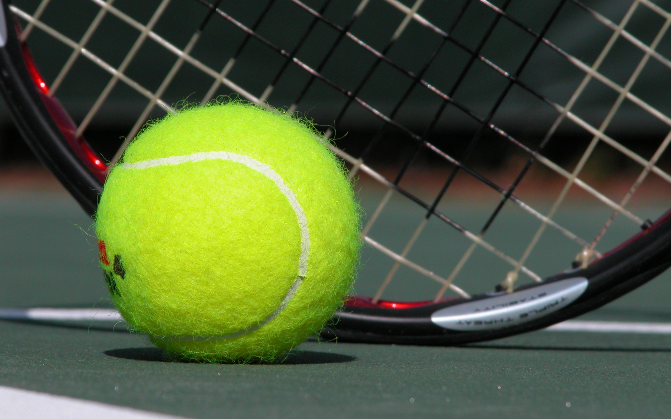 tennis ball on the ground of a tennis court with a tennis racquet behind it basic equipment for tennis