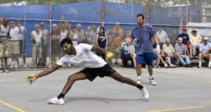 man reaching to hit the handball ball while onlookers stand in the background official equipment handball ball