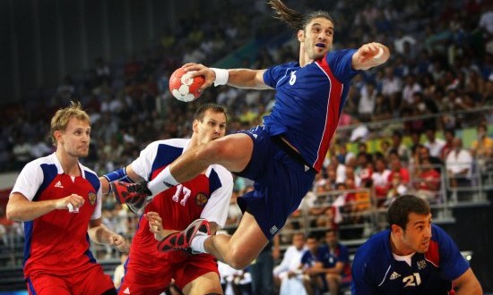 man taking a a shot on goal while jumping in the air using official regulated handball equipment ball