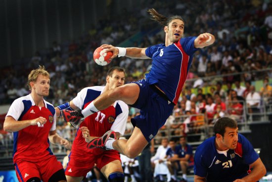 man taking a a shot on goal while jumping in the air using official regulated handball equipment ball