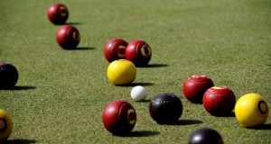 lawn bowls mid play red balls yellow ball black balls white ball basic equipment for lawn bowl different colored balls per player