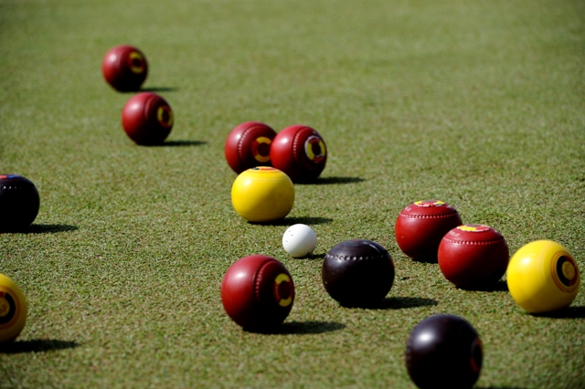 lawn bowls mid play red balls yellow ball black balls white ball basic equipment for lawn bowl different colored balls per player