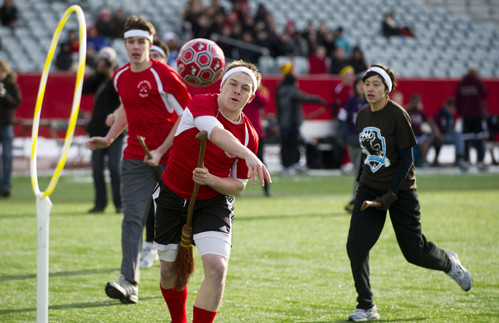 3 people in the middle of a quidditch game basic equipment for quidditch quaffle ball bludger ball snitch ball hoops on the top of poles