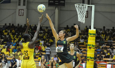 girl in green blocking shot by girl in yellow netball basic equipment ball and net hanging of a pole