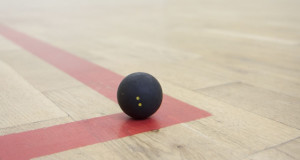black squash ball on the corner of the squash court basic equipment for squash small black squash ball