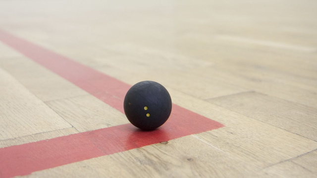 black squash ball on the corner of the squash court basic equipment for squash small black squash ball