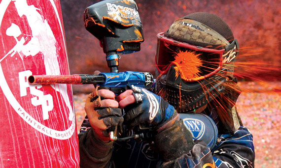 paintballer hiding behind barrier shot in the eye mask by orange paintball basic equipment paintball body gear paintball gun and paintball balls/bullets