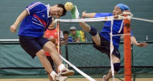 sepak takraw game one opponent is head budding the ball while the other is kicking the ball over a net that is similar to a volleyball net standard equipment for sepak takraw