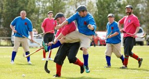 Shinty game with 3 men on blue team and 3 men on red team regulated equipment for shinty