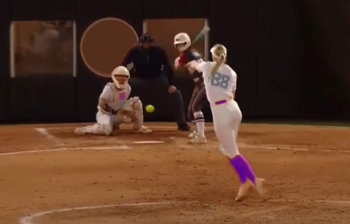 Woman pitcher throwing Windmill-style fast pitch in softball game.